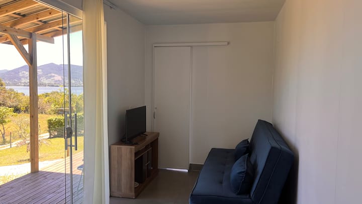 غرفة مكيفة الهواء مع تلفزيون وسرير أريكة مريح. مساحة وظيفية مع إمكانية الوصول إلى الحمام والمطبخ. 