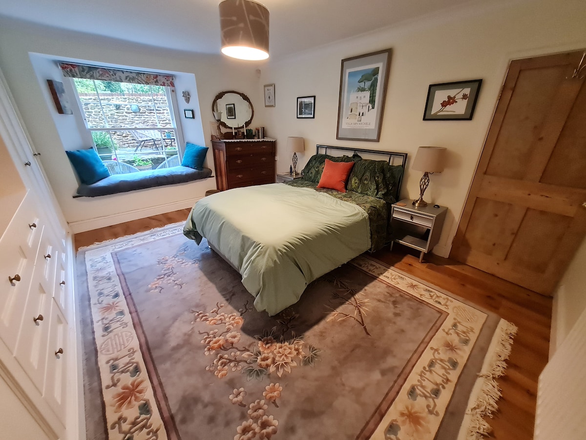 غرفة نوم مريحة واسعة مع مقعد نافذة يطل على الفناء الخاص