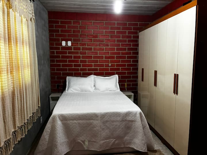 Dhomë gjumi dopio me një gardërobë, komodina dhe abazhurë të bukur leximi.