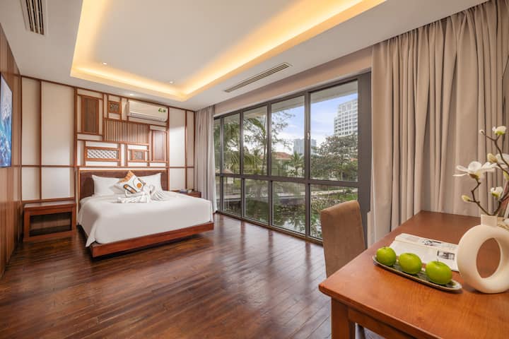 Manželská posteľ Queen sa nachádza pod prúdom jemného ranného svetla a ponúka zvýšené pohodlie. Upokojujúce tóny a čisté línie vytvárajú intímny priestor ideálny pre hostí, ktorí hľadajú jemnosť, súkromie a nádych rafinovaného luxusu.