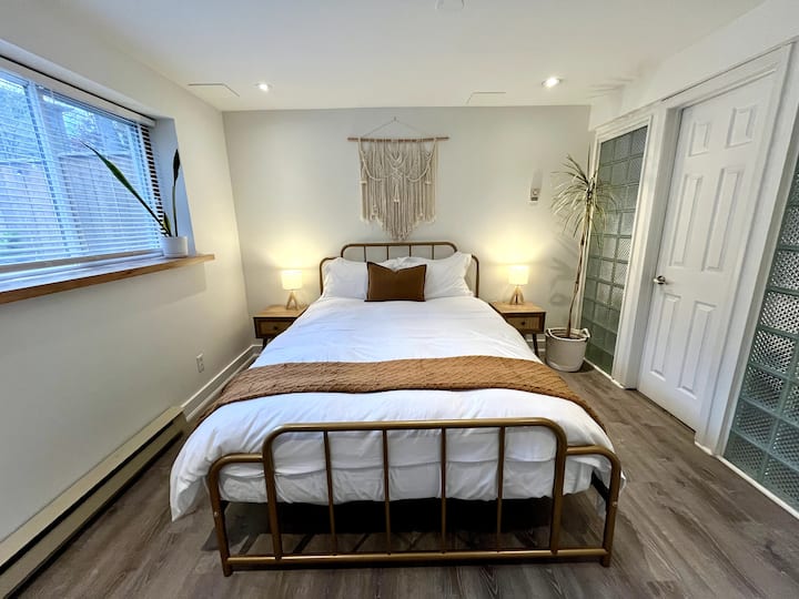 Nieuw ingerichte slaapkamer met een zeer groot raam om veel daglicht binnen te laten.  De kamer is smaakvol ingericht met een kledingkast met planken, een comfortabel queensize bed en schoon beddengoed. 