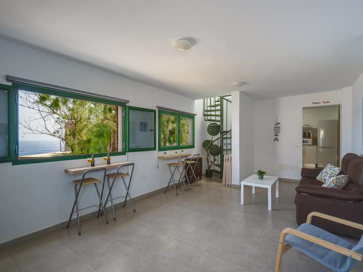 Amplio y luminoso salón-comedor con alma de Terraza rodeado de grandes ventanales, mucha luz,  aire libre y preciosas vistas al oceano y a las piscinas naturales. Un lugar diseñado para disfrutar en cualquier época.