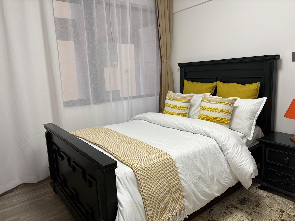 Druga spavaća soba nudi udobno i jedinstveno utočište s drvenim okvirom kreveta izrađenim po mjeri, noćnim ormarićem i upečatljivom narančastom svjetiljkom koja dodaje dašak umjetničkog stila.
