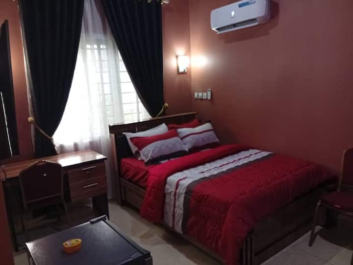 Dormitorio en suite equipado con aire acondicionado, TV inteligente con Netflix, ventilador, nevera, espejo, armario, reloj de pared y marco, mesa de lectura y sillas, etc. Electricidad 24/7 alimentada por inversor híbrido de 20 kva, generador de reserva y electricidad general.