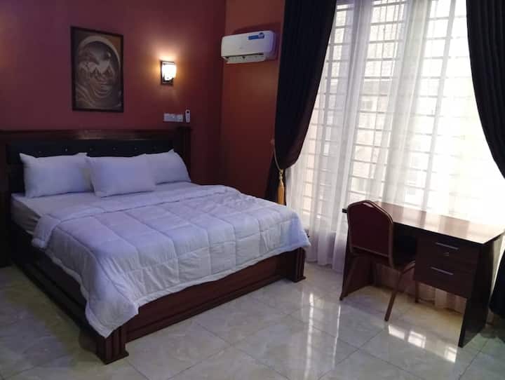 Dormitorio en suite equipado con aire acondicionado, TV inteligente con Netflix, ventilador, nevera, espejo, armario, reloj de pared y marco, mesa de lectura y sillas, etc. Electricidad 24/7 alimentada por inversor híbrido de 20 kva, generador de reserva y electricidad general.
