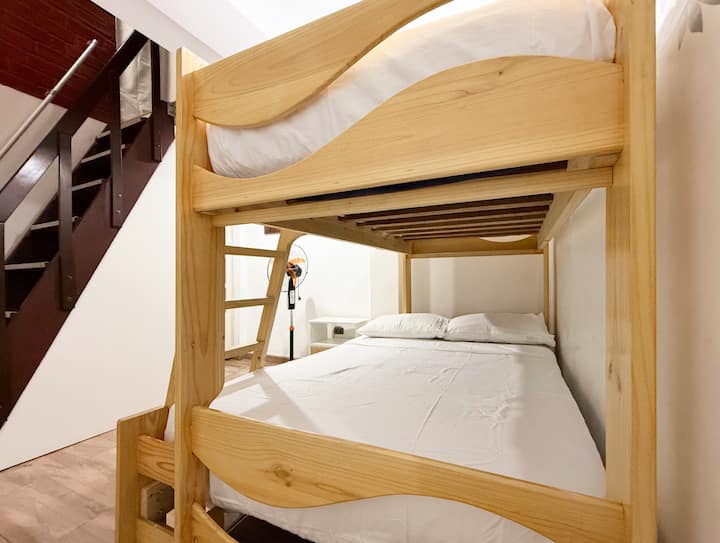 Um quarto secundário com um beliche de madeira, ideal para famílias ou grupos. Tem uma cama de casal no andar de baixo e uma cama de solteiro no andar de cima.