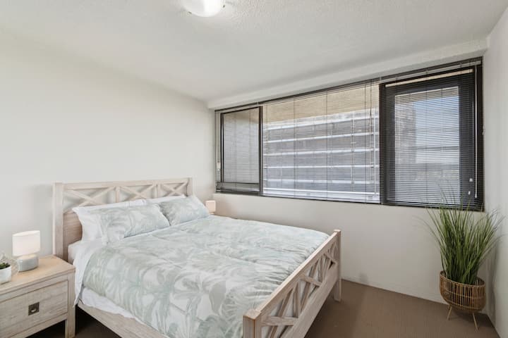 The primary bedroom features a queen bed, crisp linens, a built-in wardrobe and warm lighting for a restful night’s sleep.