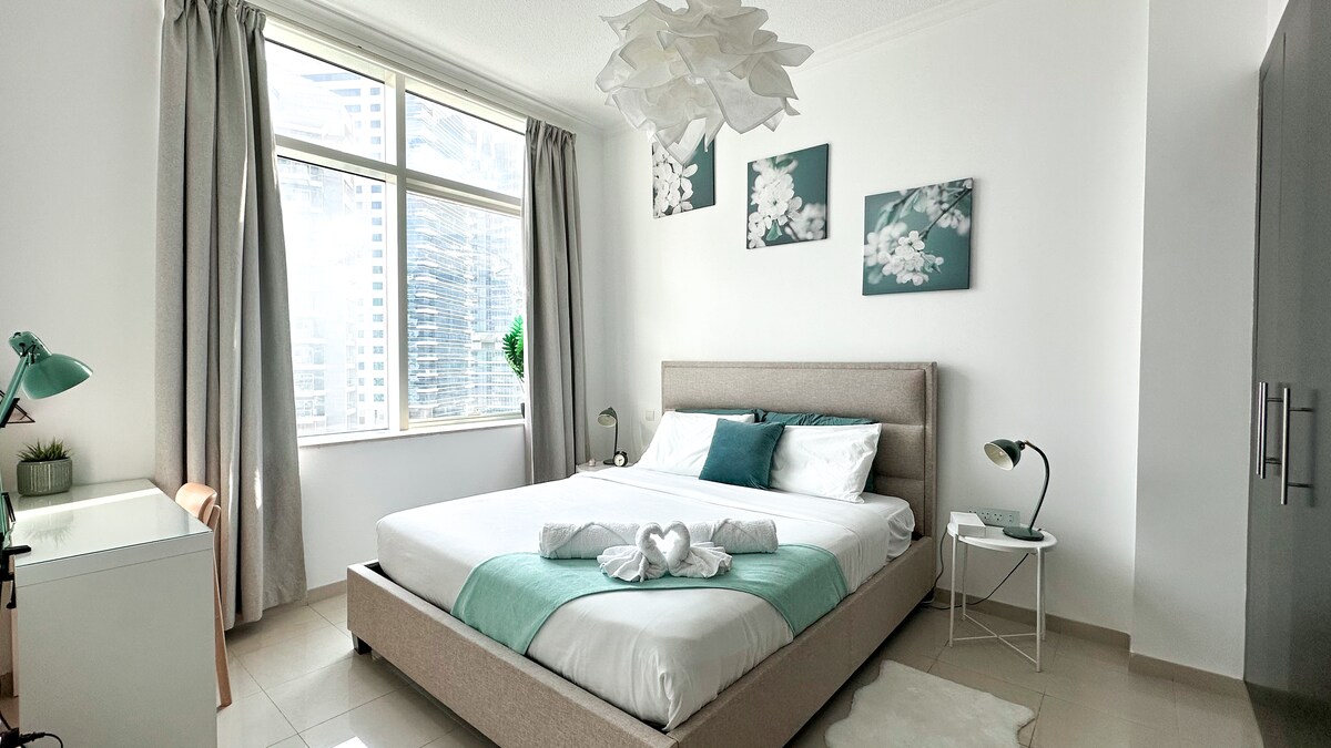 Chumba kilichobuniwa kwa ajili ya starehe na mapumziko: kitanda cha ukubwa wa king chenye godoro linalozunguka, mwanga wa asili unaoingia kutoka kwenye dirisha la ukuta mzima, dawati mahususi na bafu la kujitegemea lenye beseni la kuogea.