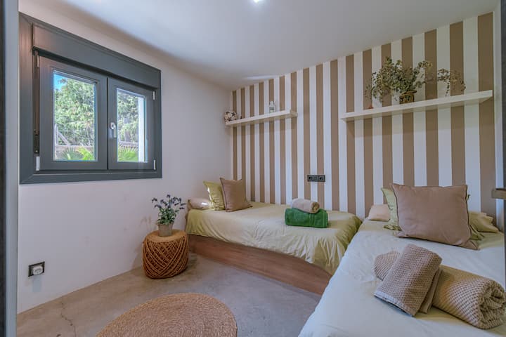 Dormitorio 3 con dos camas individuales, calefacción y ventana al jardín.