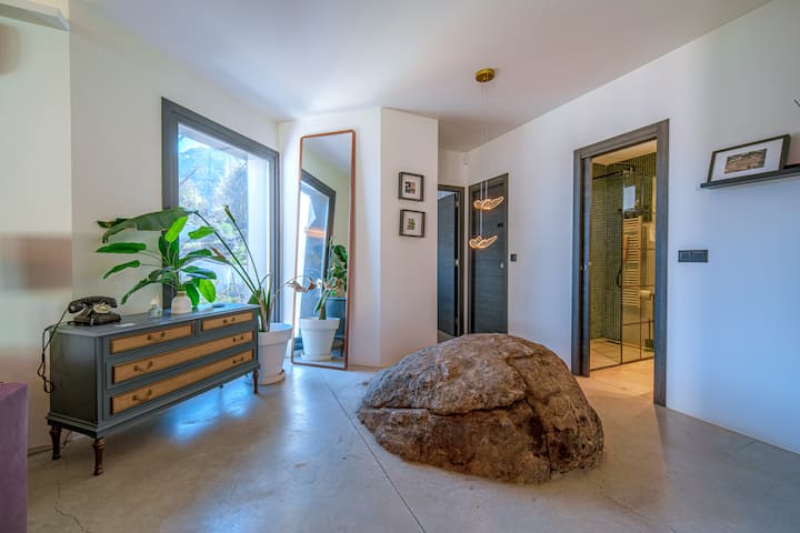 La gran roca de granito preside el recibidor, con acceso directo al pasillo de dormitorios.