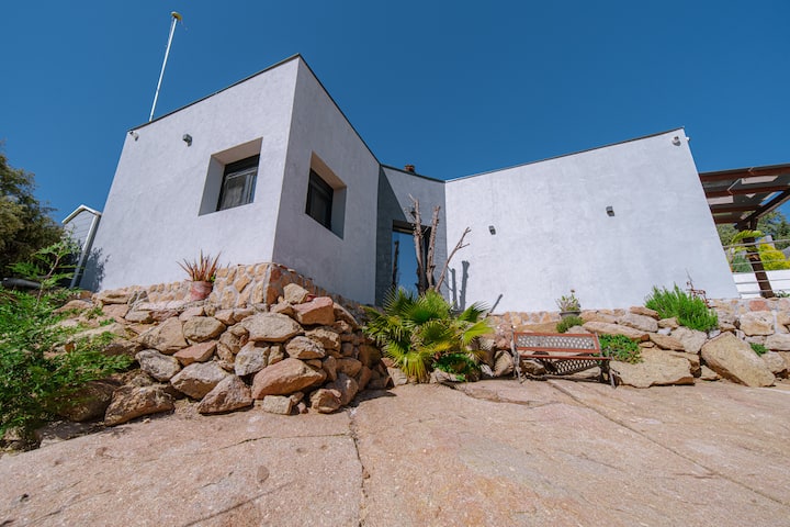 Fachada de la villa integrada en las rocas de granito, en parcela privada vallada.