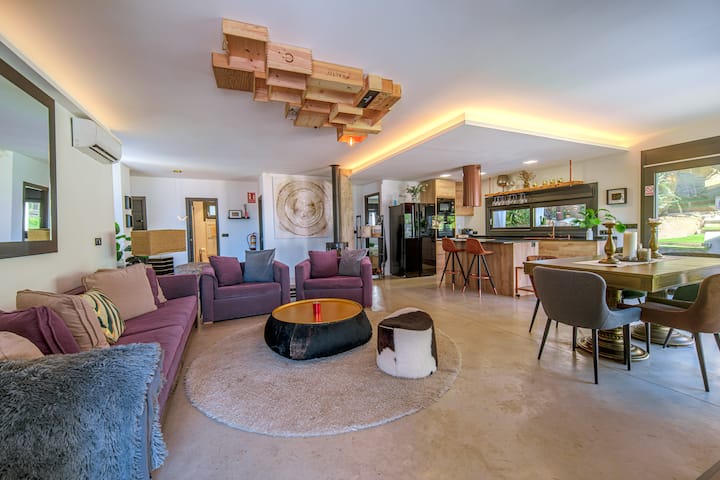 Salón de diseño con estufa de leña, aire acondicionado y sistema de sonido; luz indirecta y suelo continuo.