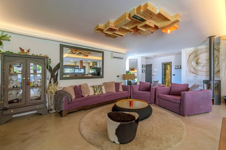 Zona de estar abierta a cocina y comedor, con aire acondicionado y salida directa al jardín.