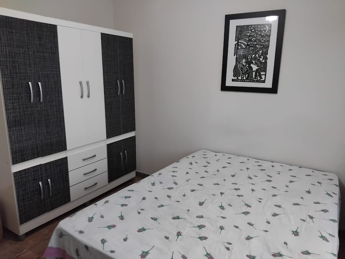 Suite avec lit double, armoire, bidet, bureau et chaise, ventilateur de plafond.