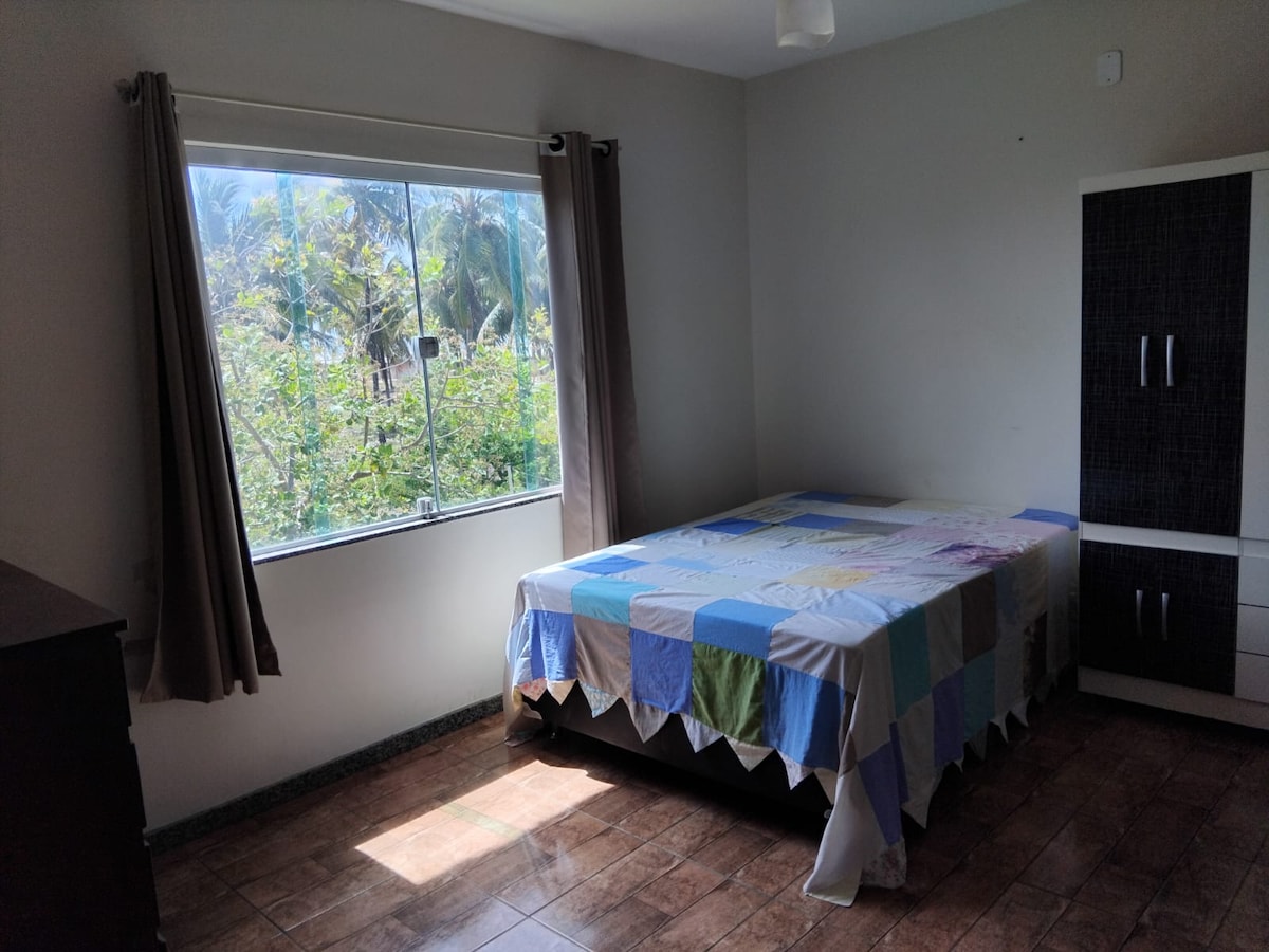 Chambre à coucher avec salle de bain privée, armoire, commode, bidet, ventilateur de plafond et ventilateur de table.
