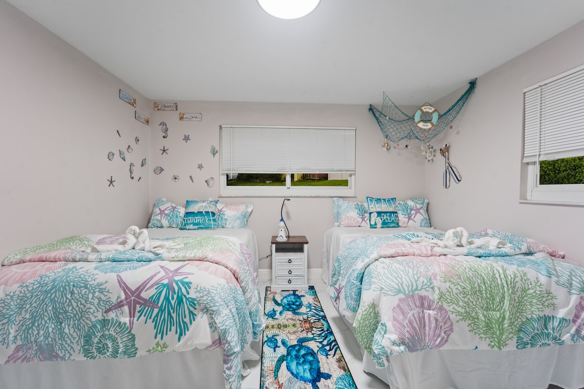 Double beds, double the fun. This cheerful coastal room pops with playful pillows, sea turtle rugs, and beachy wall art for a splash of summer energy.