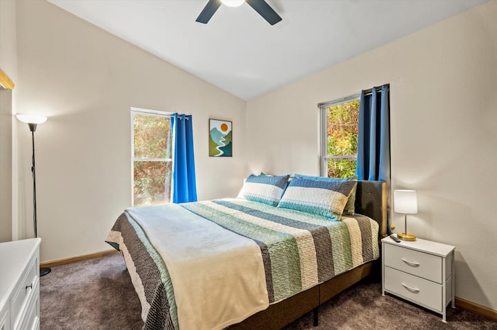 Bright King bedroom with vaulted ceilings, scenic art, and cozy bedding.