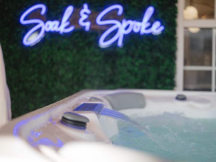 Soak & Spoke hot tub with neon sign and bathrobes