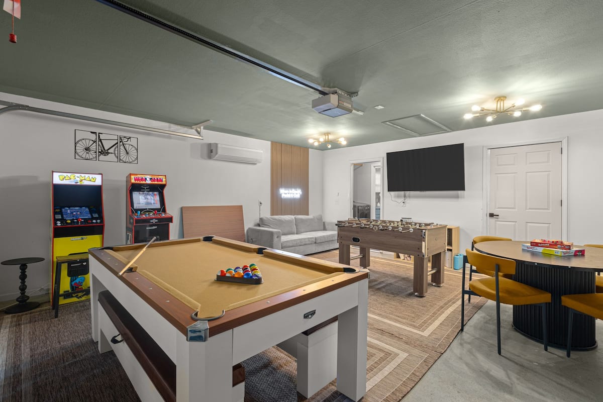 Game room with pool table, arcade machines, TV, and bicycle mural