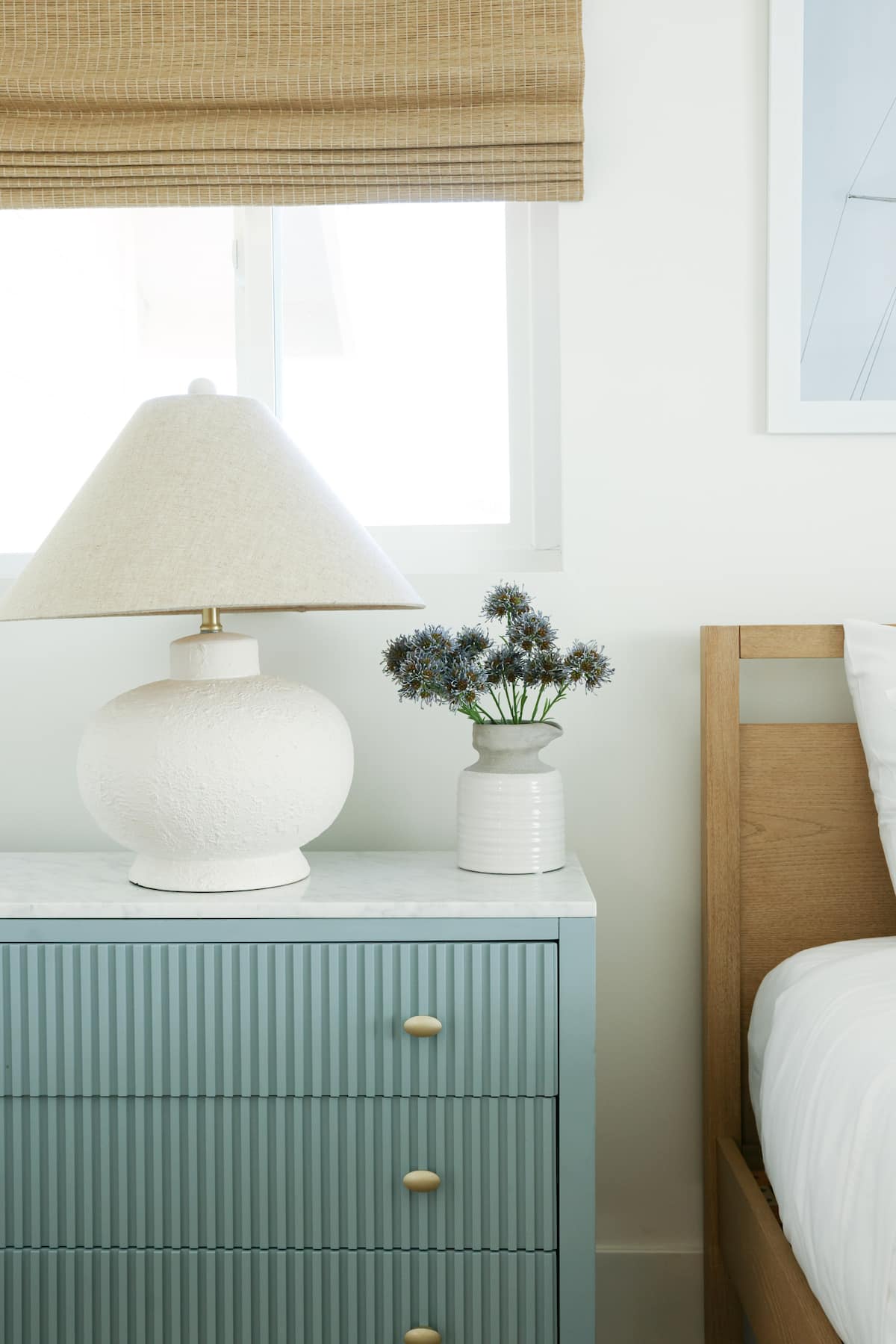 A fluted blue dresser with a ceramic lamp and fresh flowers at The Sapphire in Pacific Beach, designed by Salt and Sky Lodging Co.