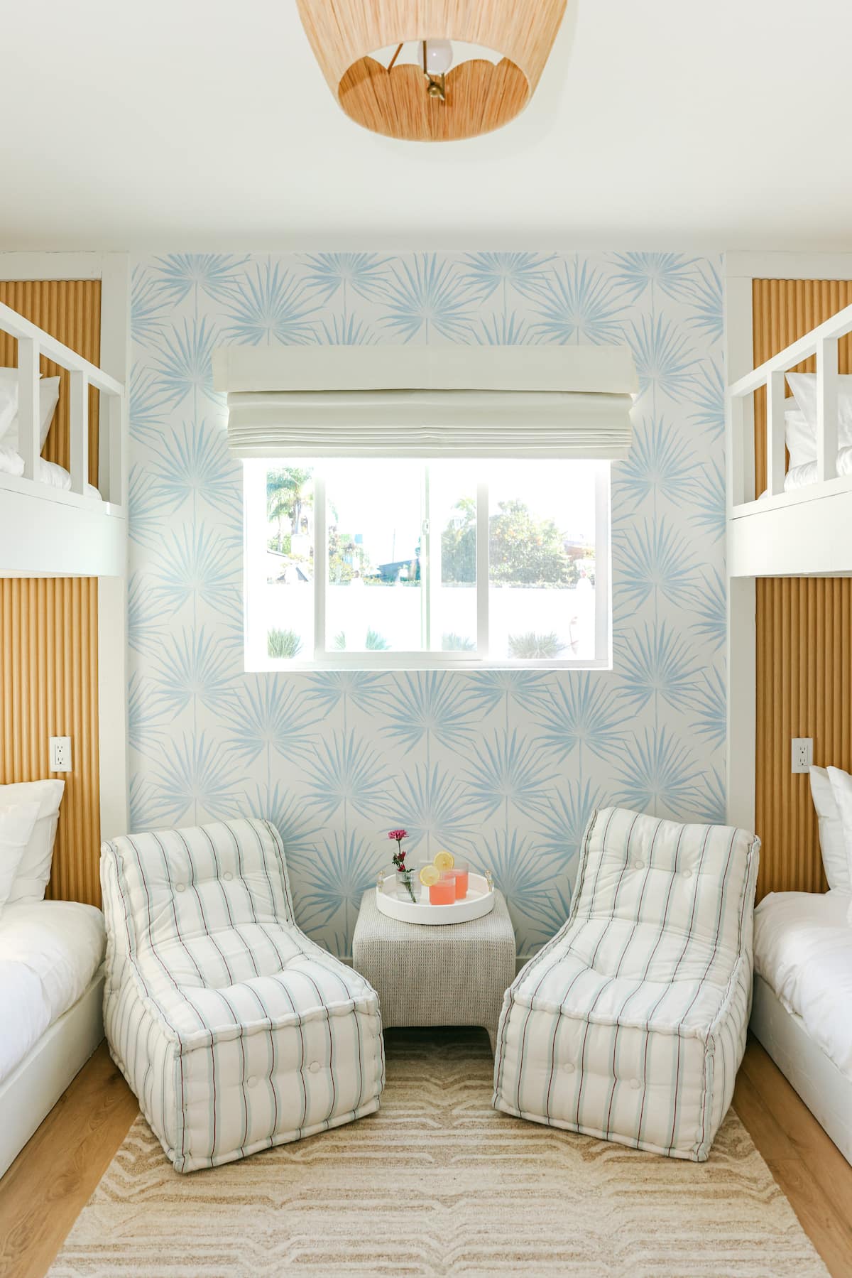 The kids bunk room with blue palm wallpaper, built in bunks and striped lounge chairs at The Sapphire in Pacific Beach, designed by Salt and Sky Lodging Co.
