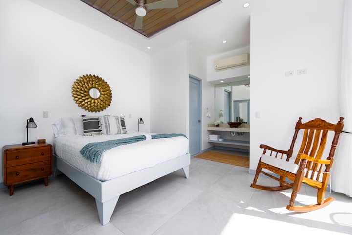 Tranquilo dormitorio tamaño queen con baño privado y balcón propio con vistas a la selva y las montañas. Disfruta del café de la mañana o de las brisas del atardecer desde la mecedora, tu propio refugio tranquilo en Casa Sunset.