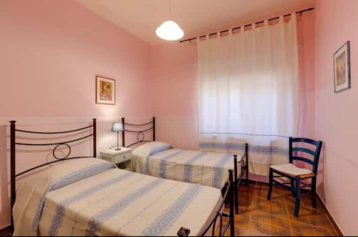 Dormitorio con dos camas individuales, mesita de noche, armario y escritorio. 
