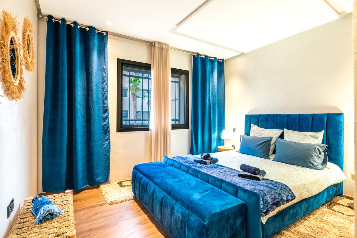 Elegante habitación de estilo moderno, decorada en tonos azul profundo para un ambiente relajante. Cama grande y cómoda, ropa de cama de calidad y luz natural para un descanso óptimo.