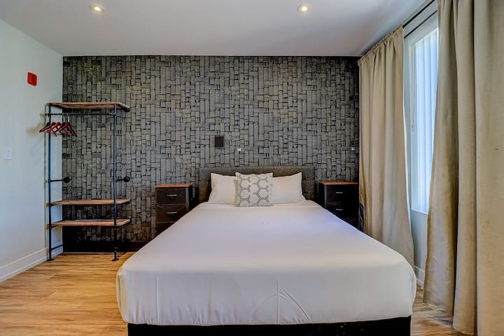 Duerme con estilo. Con una cómoda cama tamaño queen, un elegante espacio de almacenamiento industrial y una llamativa pared para una estancia moderna y relajante.