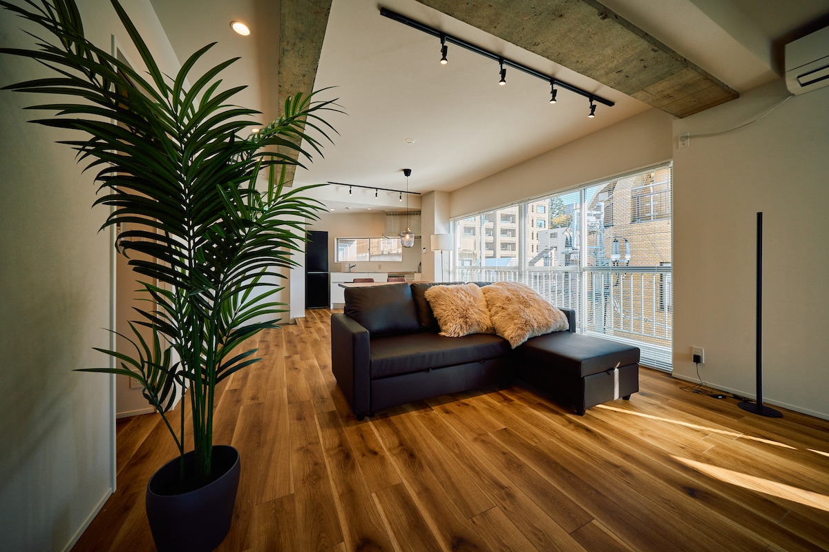 【リビング・ダイニング】約22㎡、ダブルソファベッドとダイニングテーブル6名掛け、55インチ4Kテレビを備えた最上階のくつろぎスペースです。色を自由に変えられるLEDスタンドライトでシアタールームのようにお使いいただけます。