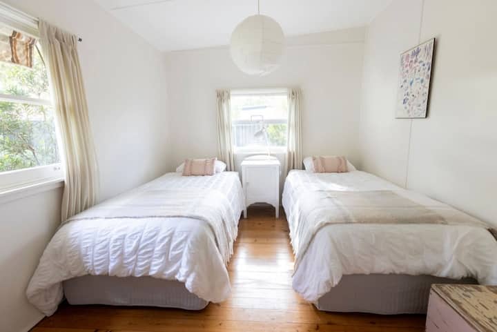 A large bedroom with 2 king single beds, and built in wardrobe.
