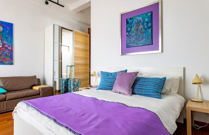 سرير كوين في غرفة نوم مع معرض فني، إطلالات على المركز التاريخي، لوحات أصلية في جميع أنحاء المكان، حمام داخلي مع حوض استحمام عميق. ملاذ إبداعي غامر مع لوحة لافندر مهدئة لراحة ملهمة.