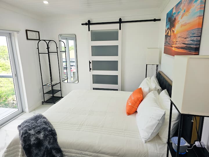 Amplio dormitorio principal abierto y espacioso con un hermoso baño privado. Cómodo colchón de espuma viscoelástica tamaño king. Televisor inteligente de 50 pulgadas en la pared con más de 3000 canales integrados.