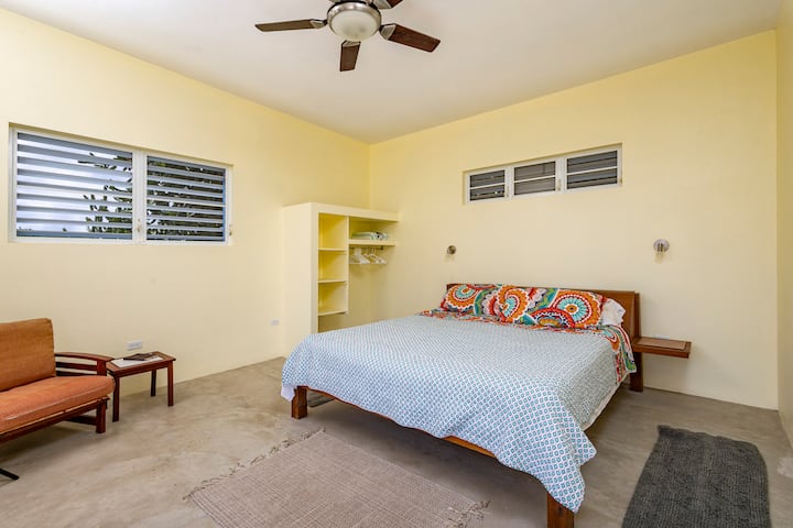 Spavaća soba ispunjena mirnoćom i sunčevom svjetlošću, čistih linija, s podovima od brušenog betona i prozorima s rešetkama kroz koje povjetarac može proći i tako osigurati miran san.