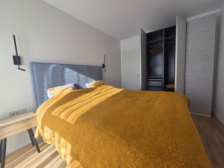 Chumba cha kulala cha kisasa chenye kitanda cha ukubwa wa kingi (1.80m x2.0m) kwa ajili ya starehe kamili. Shuka laini la kitanda lililotengenezwa Uswisi lenye mashuka ya kitani ya ubora wa juu. Kabati kubwa la nguo lenye droo na viango.