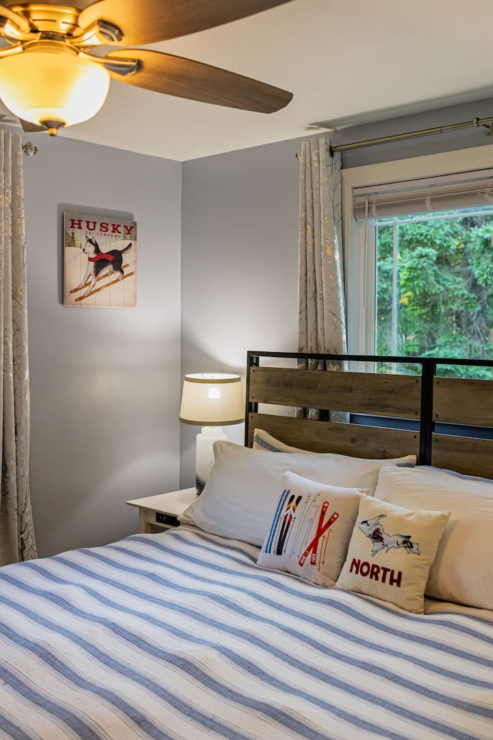 Cozy king bedroom with peaceful wooded views and charming UP-inspired touches.