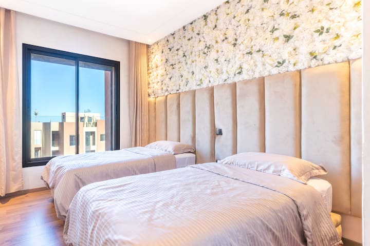 明亮的卧室，有两张舒适的床、优雅的花卉墙和大窗户，视野开阔。 柔和舒适的空间，非常适合放松入住。