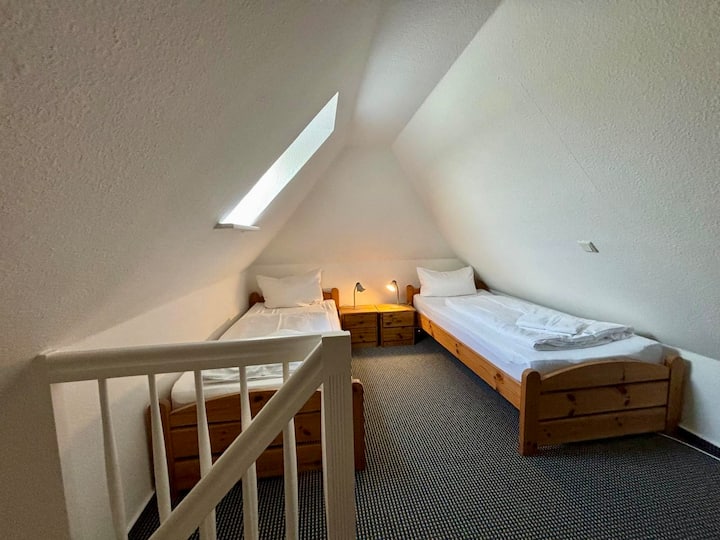 Lichte slaapkamer met twee knusse houten eenpersoonsbedden. Ideaal voor vrienden of kinderen. Nachtkastjes, beddengoed en handdoeken zijn aanwezig.