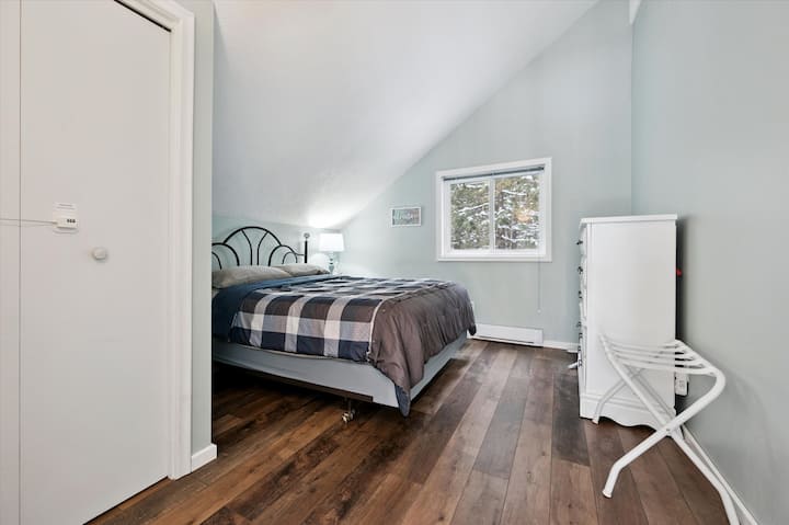Bedroom 3: Charming bedroom with queen bed, vaulted ceiling, and serene woodland views