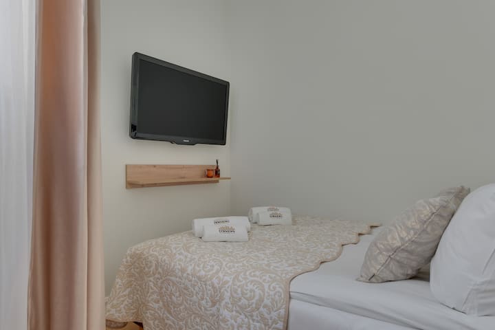 Prvá spálňa je zariadená v pokojných farbách. K dispozícii je pohodlná posteľ s rozmermi 140 × 200 cm a oproti nej televízor, čo zaisťuje možnosť relaxácie v pohodlných podmienkach.