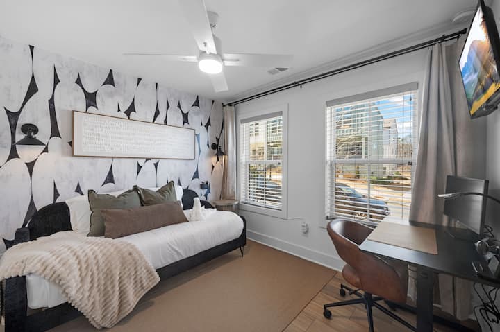 ห้องนอนสำหรับแขกที่ตกแต่งอย่างมีสไตล์ โดดเด่นด้วยผนังตกแต่งดีไซน์พิเศษ พื้นที่ทำงานที่จัดไว้อย่างเป็นสัดส่วน และแสงธรรมชาติที่ส่องเข้ามาอย่างเต็มที่