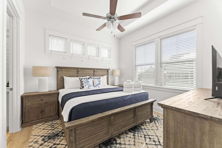 Un dormitorio principal luminoso con una cama tamaño king y luz natural suave.