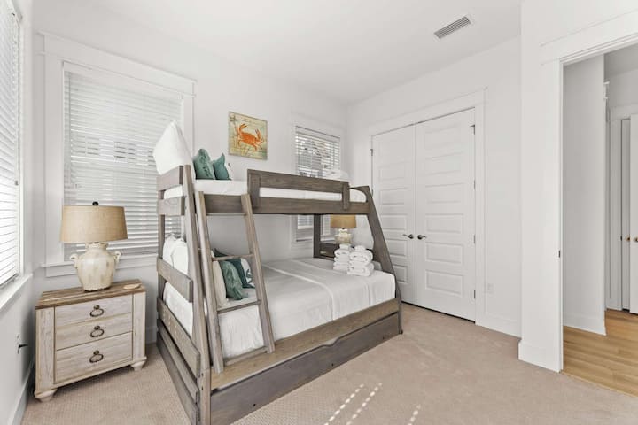 Una habitación luminosa con una litera de dos camas y luz natural suave.