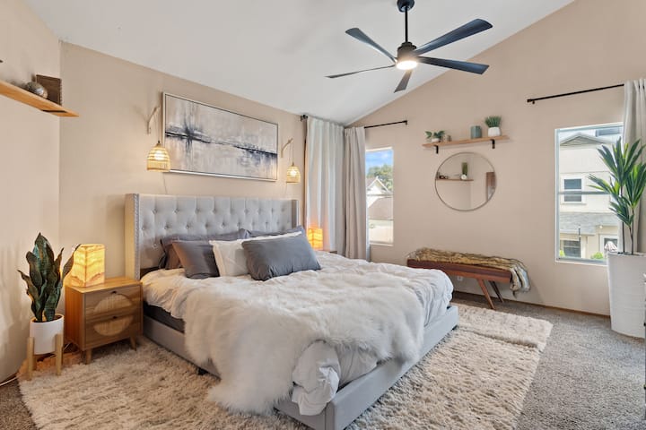 ห้องนอนใหญ่หรูหราพร้อมที่นอนสีม่วงและห้องน้ำในตัวสไตล์สปา