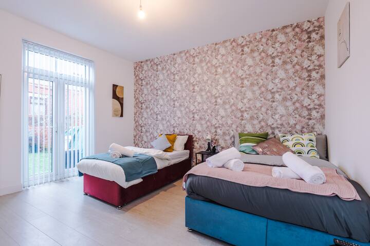 Bright and spacious bedroom with a floral feature wall and comfortable twin beds