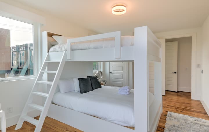 Bright, modern bunk bedroom with custom-built white bunks, featuring two queen beds. Warm wood floors, soft lighting, and clean design create a cozy, family-friendly space perfect for kids, guests, or group stays.