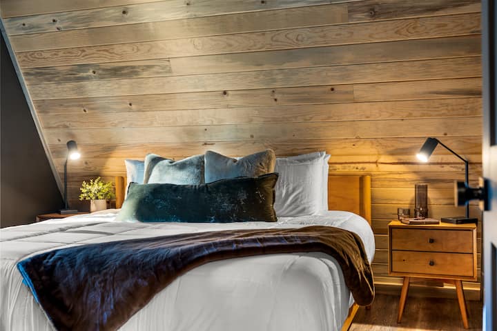 The main-level bedroom is conveniently located just across from the kitchen and features a luxurious king bed, 50" smart TV, premium bedding, and cozy robes for your stay.
