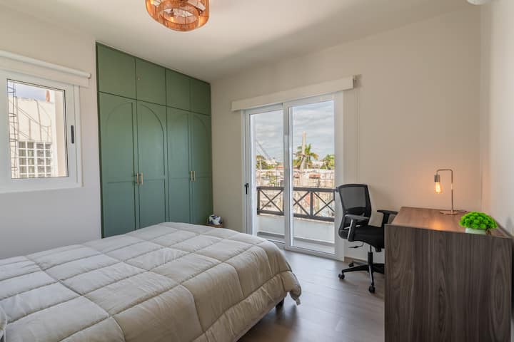 Chumba cha kulala chenye mwanga na utulivu chenye kitanda cha ukubwa wa kifalme, kabati la nguo la kijani lililojengwa ndani na roshani binafsi. Mwanga wa asili na rangi tulivu huunda sehemu ya kupumzika inayofaa kwa ajili ya kupumzika au kufanya kazi kwa starehe.