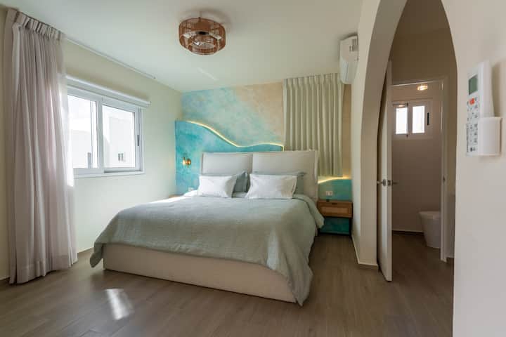 
Chumba cha kulala chenye mwanga na starehe chenye kitanda cha kifahari, mashuka laini na ukuta wa maridadi wa rangi ya samawati. Mwanga wa joto na mistari safi huunda mazingira ya kupumzika, bora kwa usiku wa kupumzika baada ya siku ya kuvinjari.