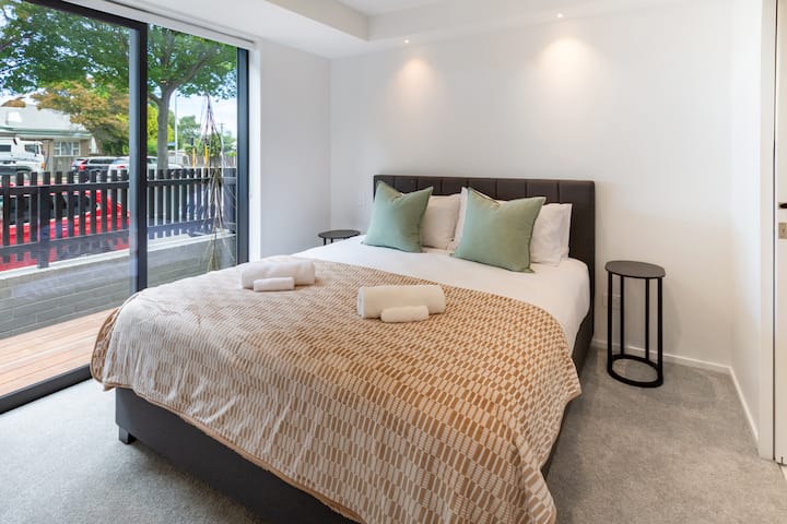 Dormitorio tamaño king con iluminación natural, toallas limpias y la cama está cubierta con sábanas de calidad hotelera.